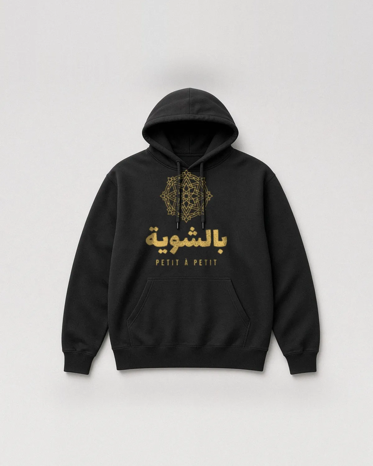 Hoodie noir avec le design « Bchwiya » : le mot arabe بالشوية sous une rosace géométrique, avec « Petit à petit » (vue de face, à plat)